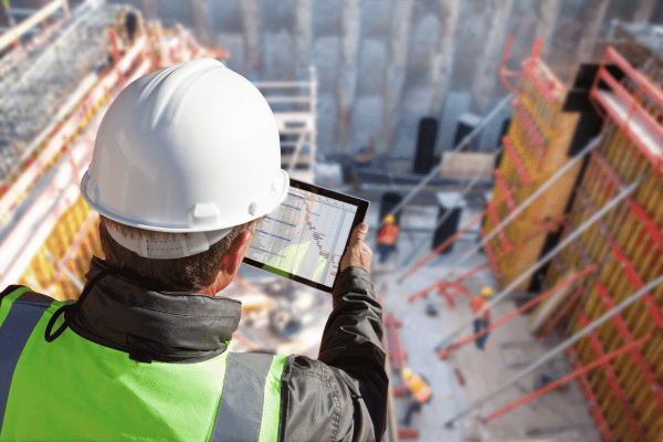 Inspector in a hard hat using a tablet on a construction site
